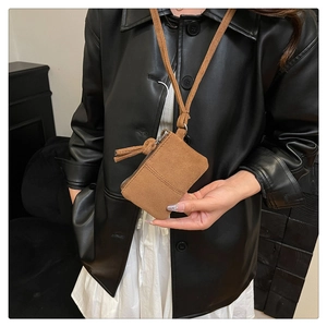 Detail of brown faux suede neck wallet with decorative stitching and zipper tassel