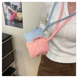 Close-up of mini neck-strap zipper bags in light blue and pink suede with stitching