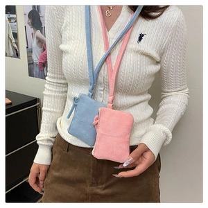 Detail view of mini neck pouches in light blue and pink suede with slim shoulder straps
