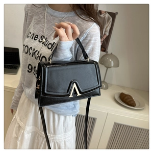Detail of black leather handbag featuring a golden A-shaped metal logo buckle