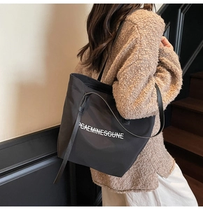 Détail du grand sac cabas noir en toile montrant la texture du tissu et le lettrage blanc
