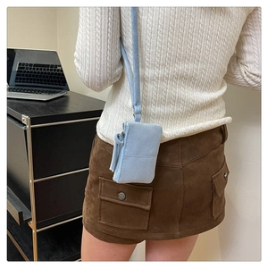 Detailed back view of a light blue suede neck pouch and lipstick bag on a model