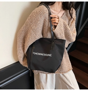 Détail du sac fourre-tout en toile noire avec imprimé lettres et larges bandoulières
