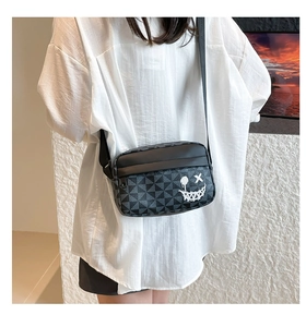 Detail of crossbody square bag featuring geometric pattern and skull smiley graffiti print