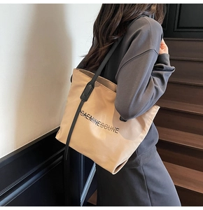 Détail d'un grand sac cabas en toile beige avec bandoulière et imprimé lettres