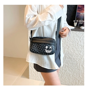 Close-up of stylish crossbody bag with geometric pattern and graffiti smiley face design