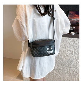 Detailed view of crossbody camera bag with grey monogram print and white graffiti smiley