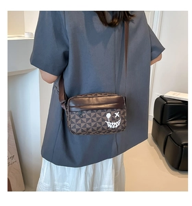 Close-up of brown geometric crossbody bag with a graffiti smile and wide strap