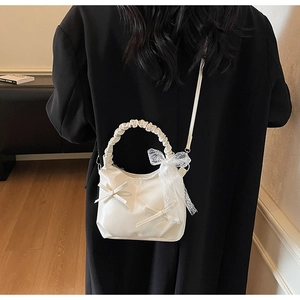 Detail of hobo bag with lace bow decoration and ruched handle on black coat background