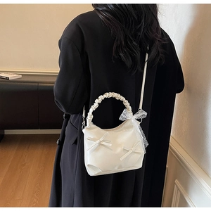 Close-up of ruched handle and bow details on a cream-white PU leather pleated bag