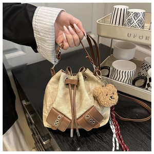 Close-up of retro canvas bucket bag with leather drawstring and brown bear keychain