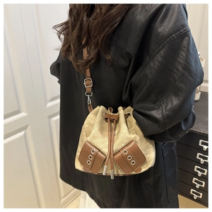 Canvas bucket bag detail with brown leather trim and drawstring on model's shoulder