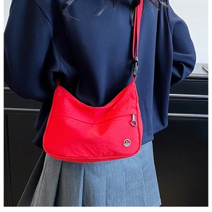 Detail of red waterproof nylon crossbody bag with metallic M logo and adjustable strap
