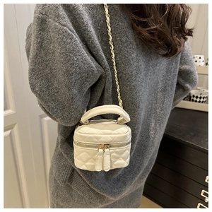 Detail of white quilted crossbody mini bag with chain strap worn by a model