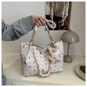 Close-up of white floral tote bag with cute bear print and pearl chain accessory