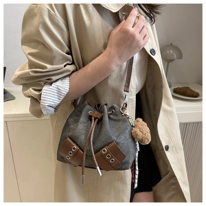 Detail of grey canvas bucket bag with brown leather drawstring and cute bear pendant