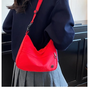Model wearing a red nylon crossbody bag with adjustable strap and metal logo detail