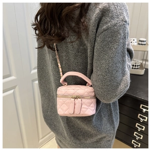 Detail of pink quilted mini bag with gold chain strap worn over a grey sweater