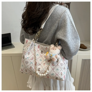 Détail du cabas floral avec bandoulière en perles et breloque ours dans un décor quotidien