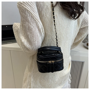 Close-up of black quilted leather vanity bag with gold chain strap and luxury hardware