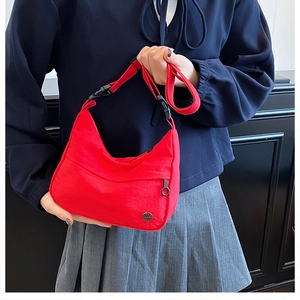 Detail of red nylon hobo bag featuring adjustable strap and buckle on model with hoodie
