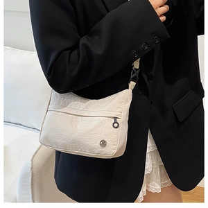 Detail of off-white nylon shoulder bag with wrinkled texture and round metal logo