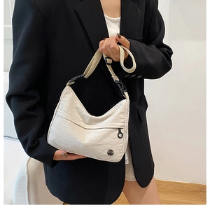 Close-up of white nylon half-moon crossbody bag featuring textured fabric and zip pocket