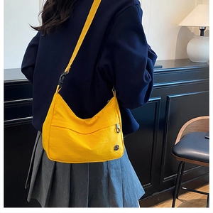 Detail of bright yellow nylon crossbody bag with zipper pocket and adjustable strap