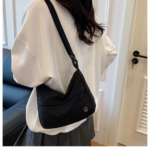 Detail of a black nylon crossbody bag featuring an adjustable strap and metal M logo