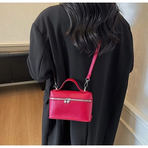 Détail du mini sac en cuir rouge avec fermetures éclair coeur sur le dos d'un mannequin