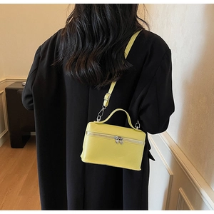 Detail of bright yellow textured leather crossbody bag with heart shaped metal zipper pull