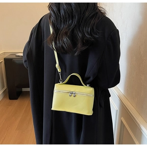 Sac bandoulière jaune citron avec zips cœur sur un mannequin en manteau noir