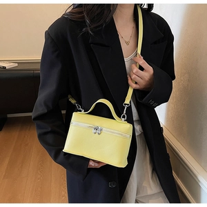 Détail du mini sac bandoulière jaune en cuir grainé avec finitions métalliques argentées