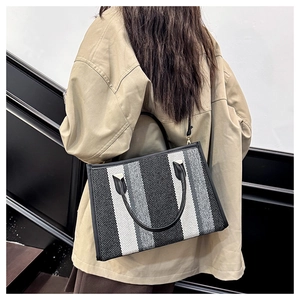 Vertical striped tote bag in black white and gray with leather handles on model