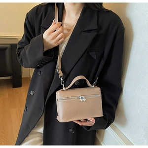Detail of light brown leather box bag with heart zippers and silver hardware