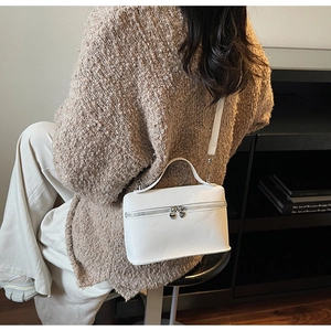 Détail de la texture en cuir litchi blanc et fermeture éclair cœur argentée sur le sac box