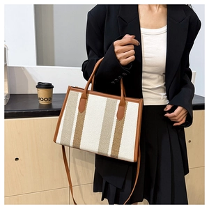 Detail of vintage striped tote bag with leather handles shown in professional workplace setting