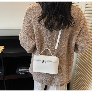 Détail du sac à bandoulière en cuir blanc texturé avec zip argenté et poignée