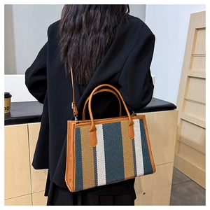 Detail of multi-color striped canvas tote bag with brown leather handles in a chic interior