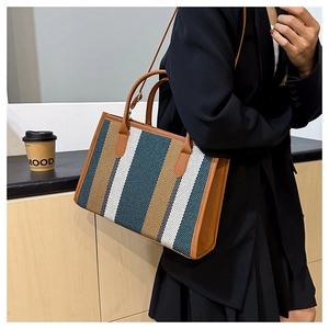Close-up of stylish striped tote bag featuring brown leather straps and spacious design