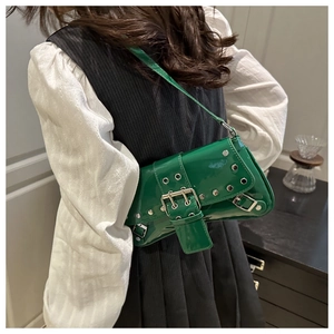 Detail view of a glossy green patent leather underarm bag with silver rivets and buckle
