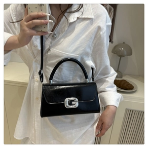 Détail du sac à main noir brillant avec boucle en cristal G et poignée métallique