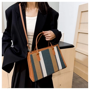 Detailed view of the striped tote bag with leather trim and adjustable shoulder strap