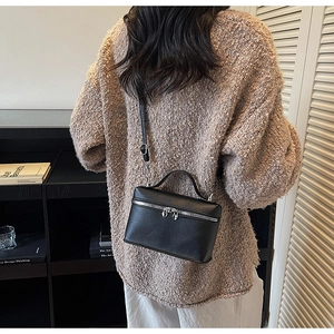 Détail du sac bandoulière en cuir noir avec de jolies breloques de fermeture en forme de cœur