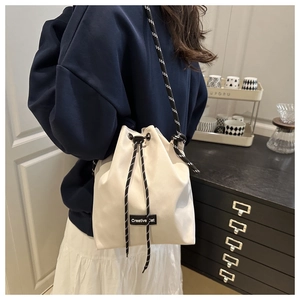 Détail du sac seau crème avec étiquette Creative Cat et bandoulière en corde tissée