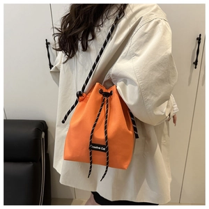 Détail du sac seau orange à cordon avec étiquette Creative Cat et bandoulière tissée