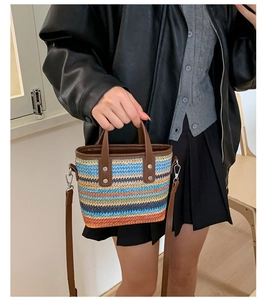 Détail d'un sac seau tissé à rayures colorées avec poignée en cuir marron et rivets