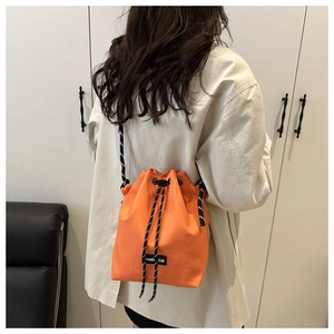 Détail du sac seau en nylon orange avec fermeture à cordon et bandoulière en corde