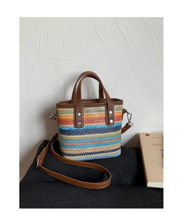 Close-up of rainbow woven tote bag featuring leather handles and silver metal hardware