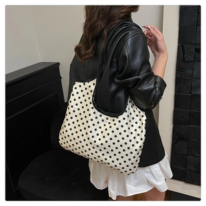 Polka dot tote bag on shoulder with minimalist black and white interior setting